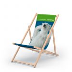 Liegestuhl aus Holz mit blau Liegefläche und Aufdruck eines Eisbären mit hinter dem Kopf verschänkten Pfoten, Schriftzug am oberen Rand der Leigefläche auf Grün in weiß " die berliner Energie - Gasag"